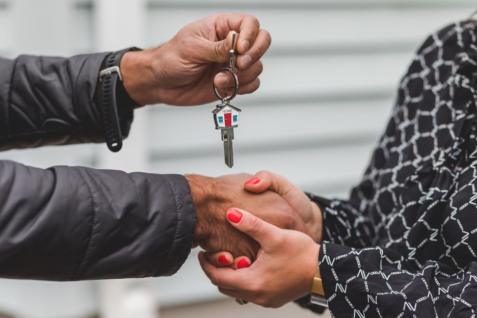A mortgage broker hands keys to a mortgage customer.