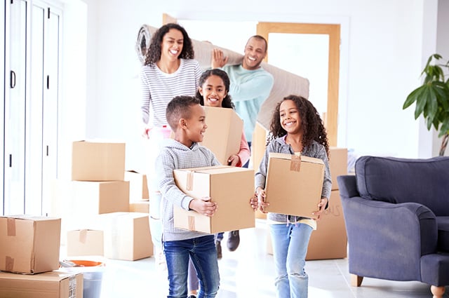 Young, happy family carries moving boxes and moves into new home.