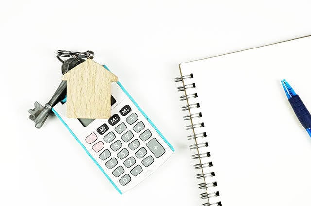 Blank notebook next to calculator and a set of house keys.